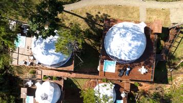 An aerial view of a resort with multiple dome-shaped structures, wooden decks, and outdoor seating areas.