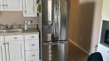 A kitchen with white cabinets, a stainless steel refrigerator, and a tiled floor.