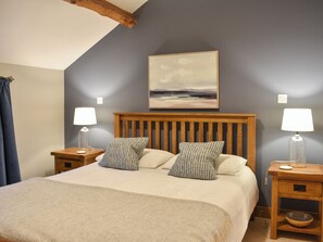 A bedroom with a wooden headboard, two bedside tables with lamps, a large bed with patterned pillows, and a painting on the wall. - Pippa's Cottage - UK42332 (Greystoke, near Penrith)