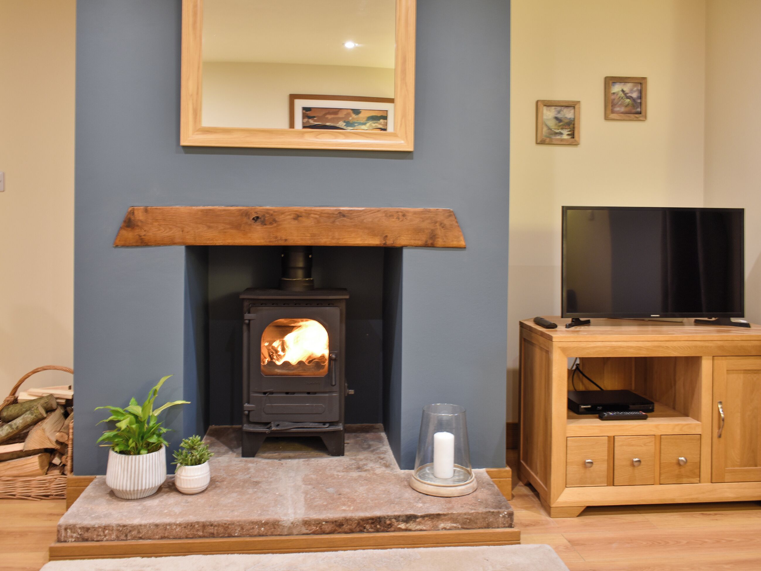 A living room with a wood-burning stove, a television, and a cabinet.