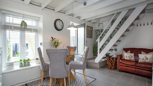 Ein Essbereich mit Tisch und Stühlen, eine Uhr an der Wand und eine Treppe, die zu einer anderen Ebene führt.