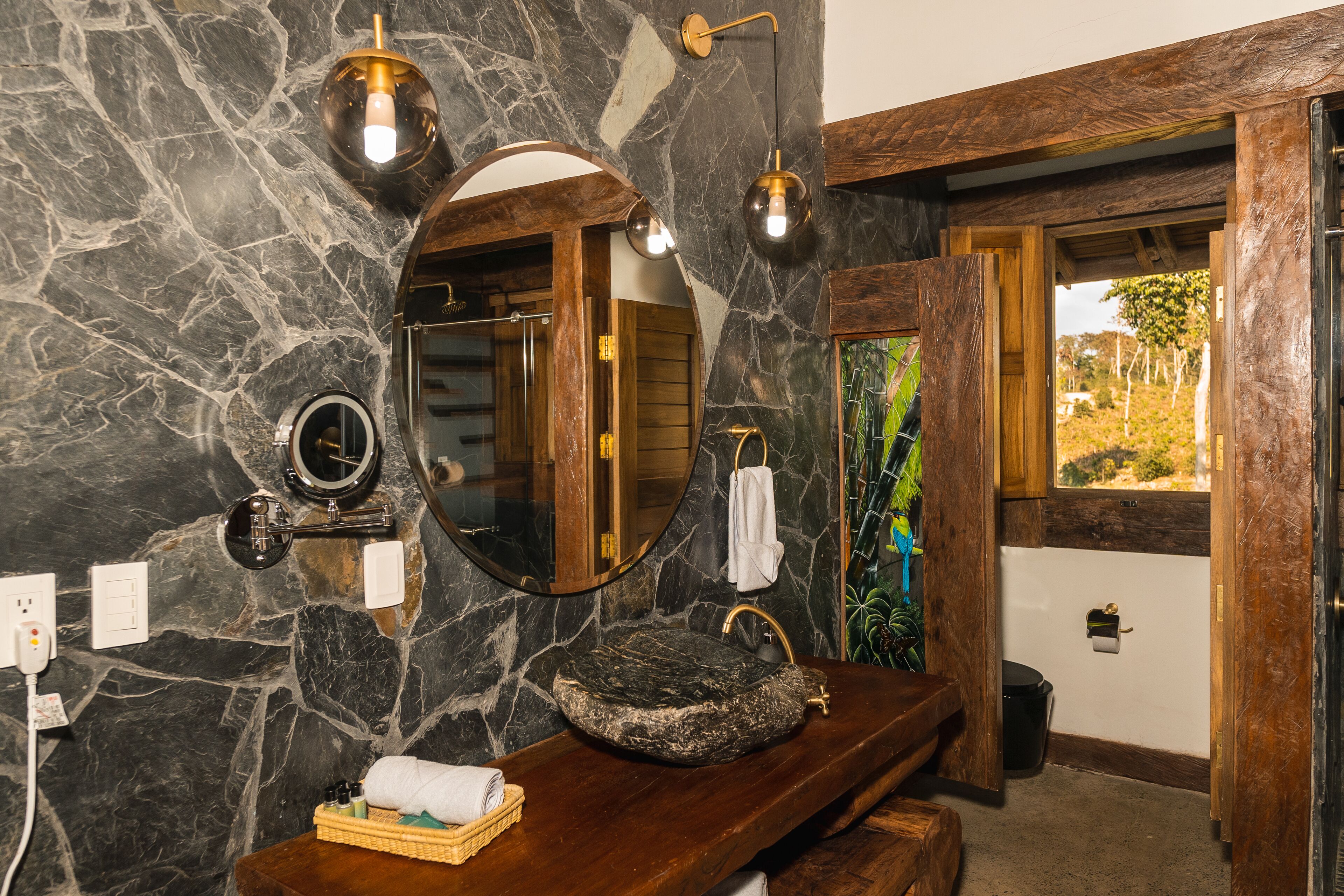A bathroom with a stone sink, wooden vanity, and a large mirror.
