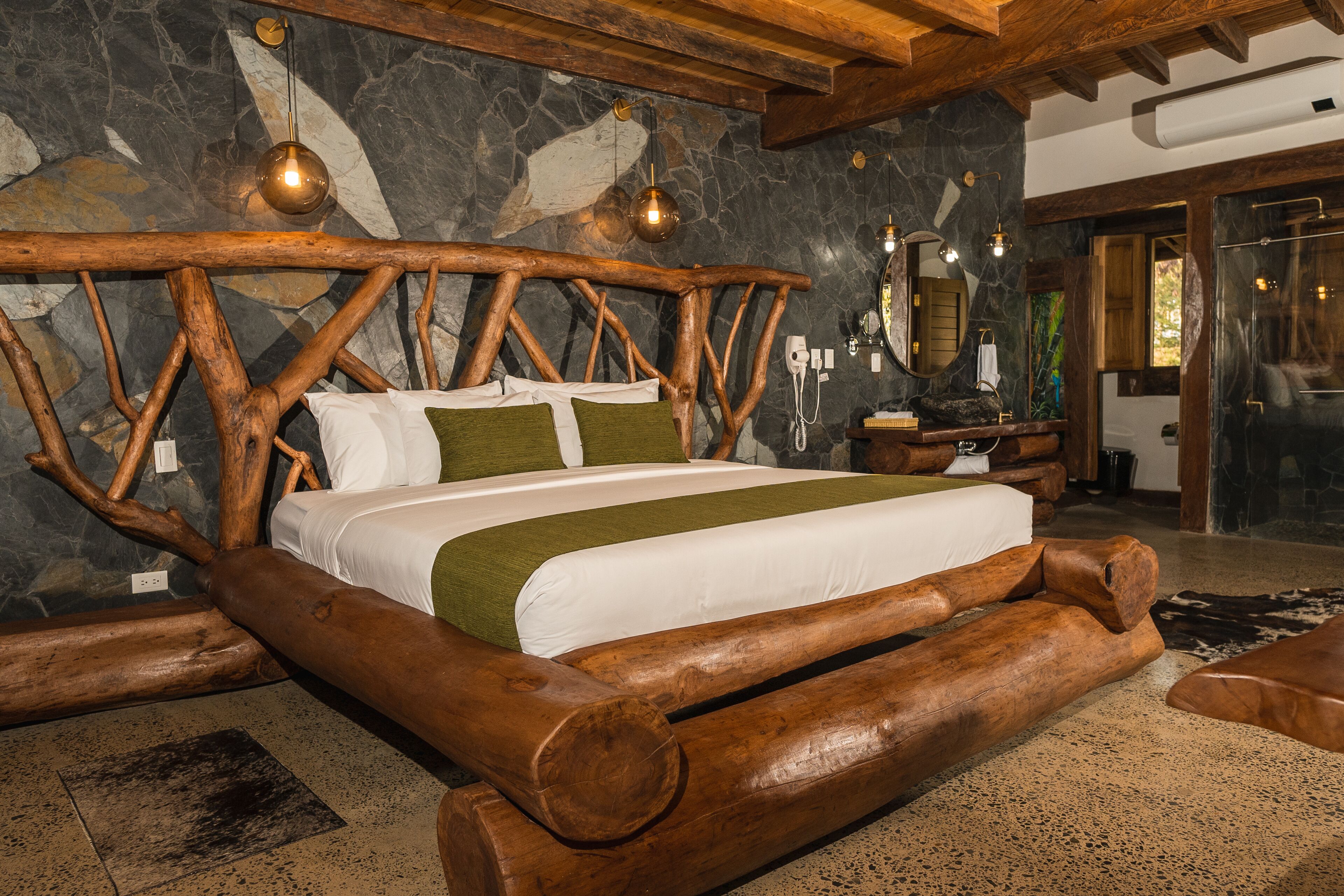 A rustic wooden bed with a stone wall backdrop and a stone floor.
