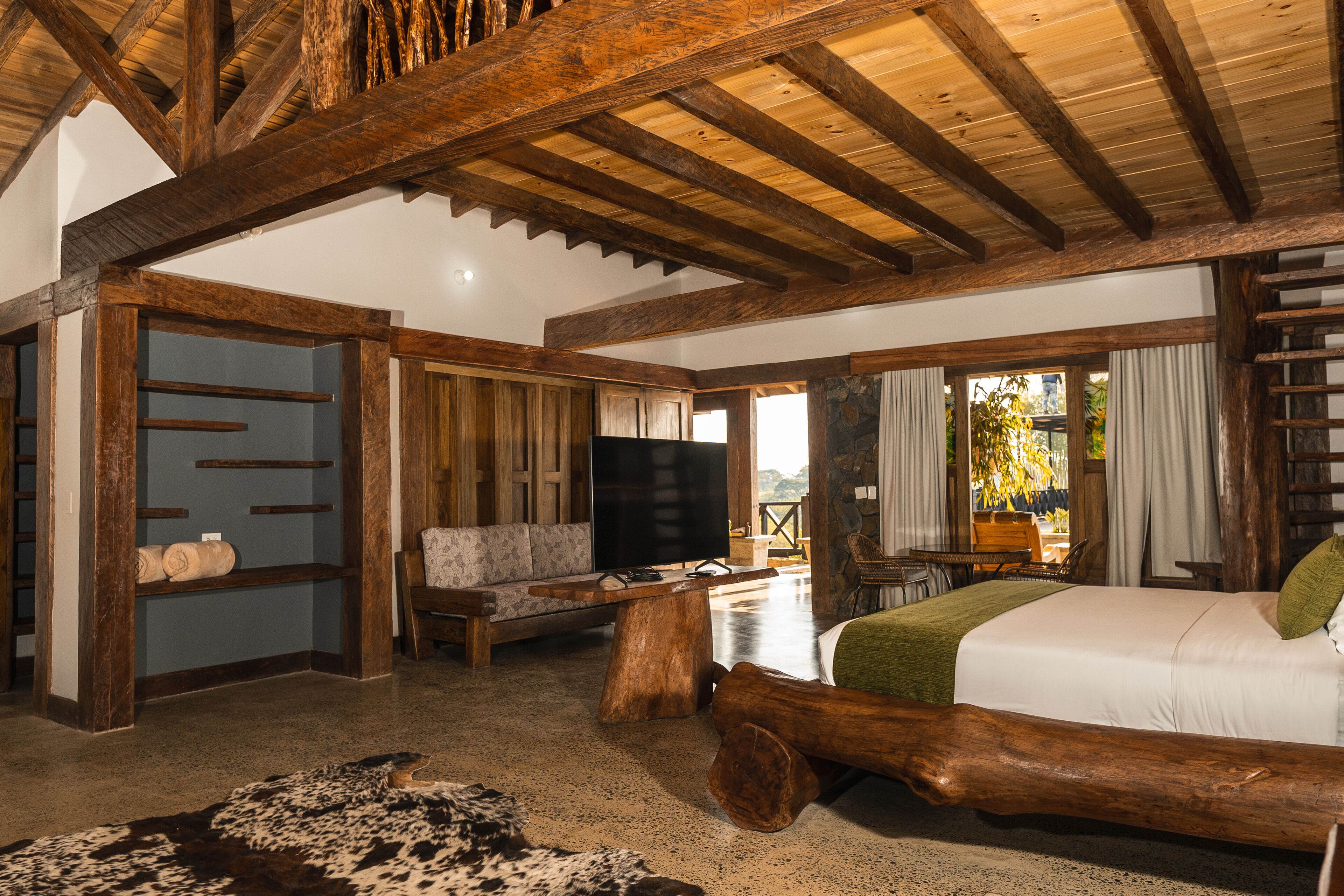 Un'ampia stanza con un letto grande, mobili in legno, una televisione e un muro in pietra.