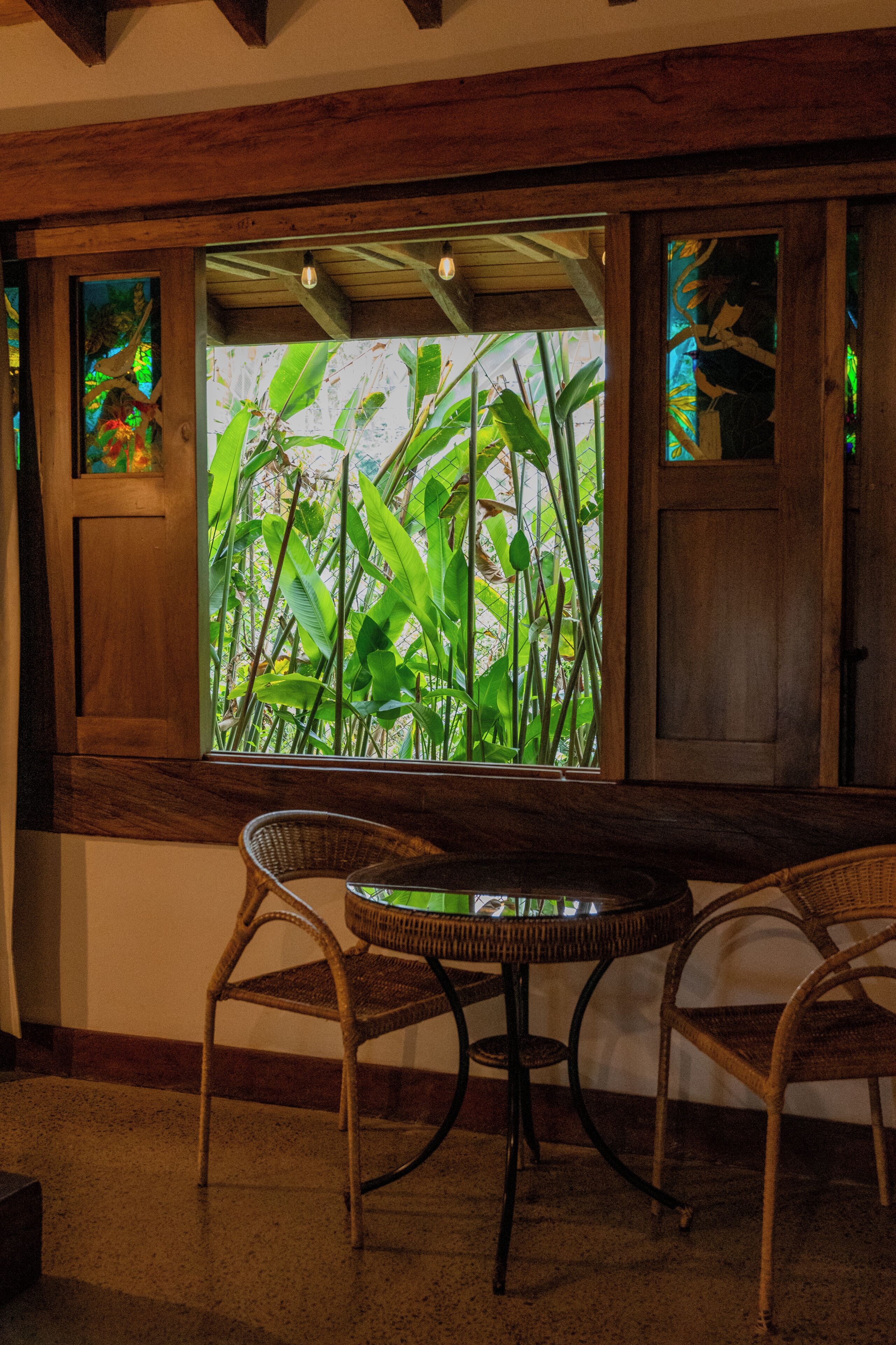 A room with a large window, wicker chairs, and a small table.