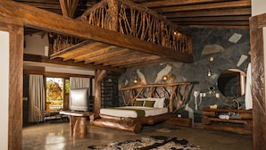 Een landelijke slaapkamer met een stenen muur, een houten bedframe en een grote spiegel.