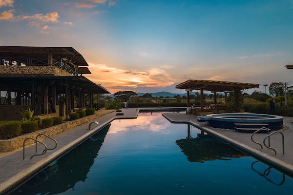 Una piscina al aire libre, sombrillas, sillones reclinables de piscina