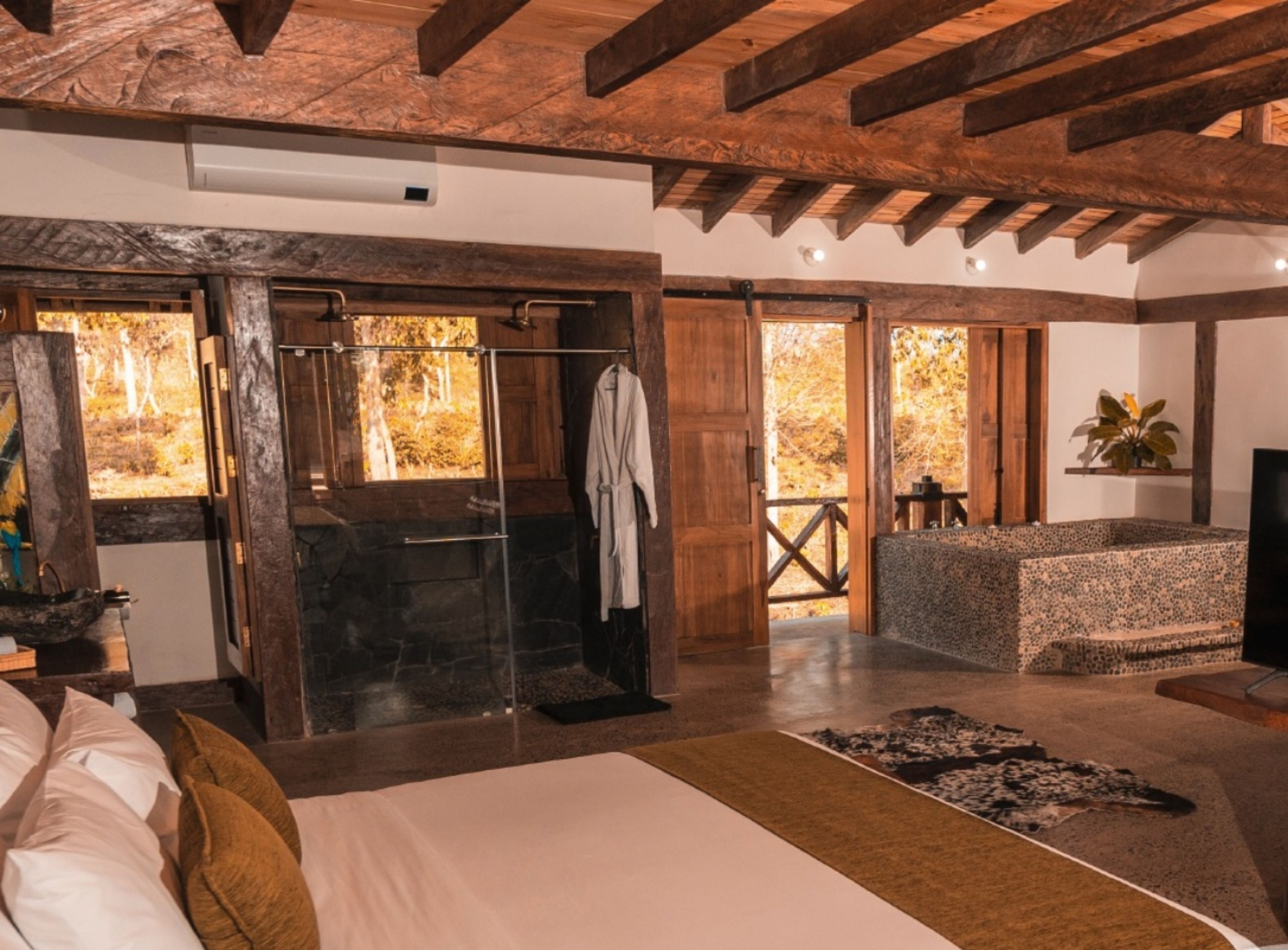 Un dormitorio amplio con una cama grande, un vestidor y zona de ducha con mampara de vidrio.