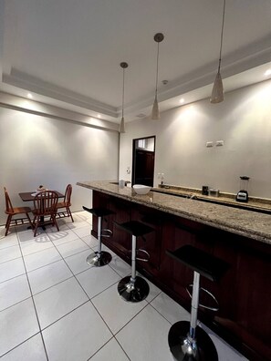 Enjoy meals in this kitchen with a sink and stainless steel range hood, accompanied by a dining area with a wooden table and four chairs.