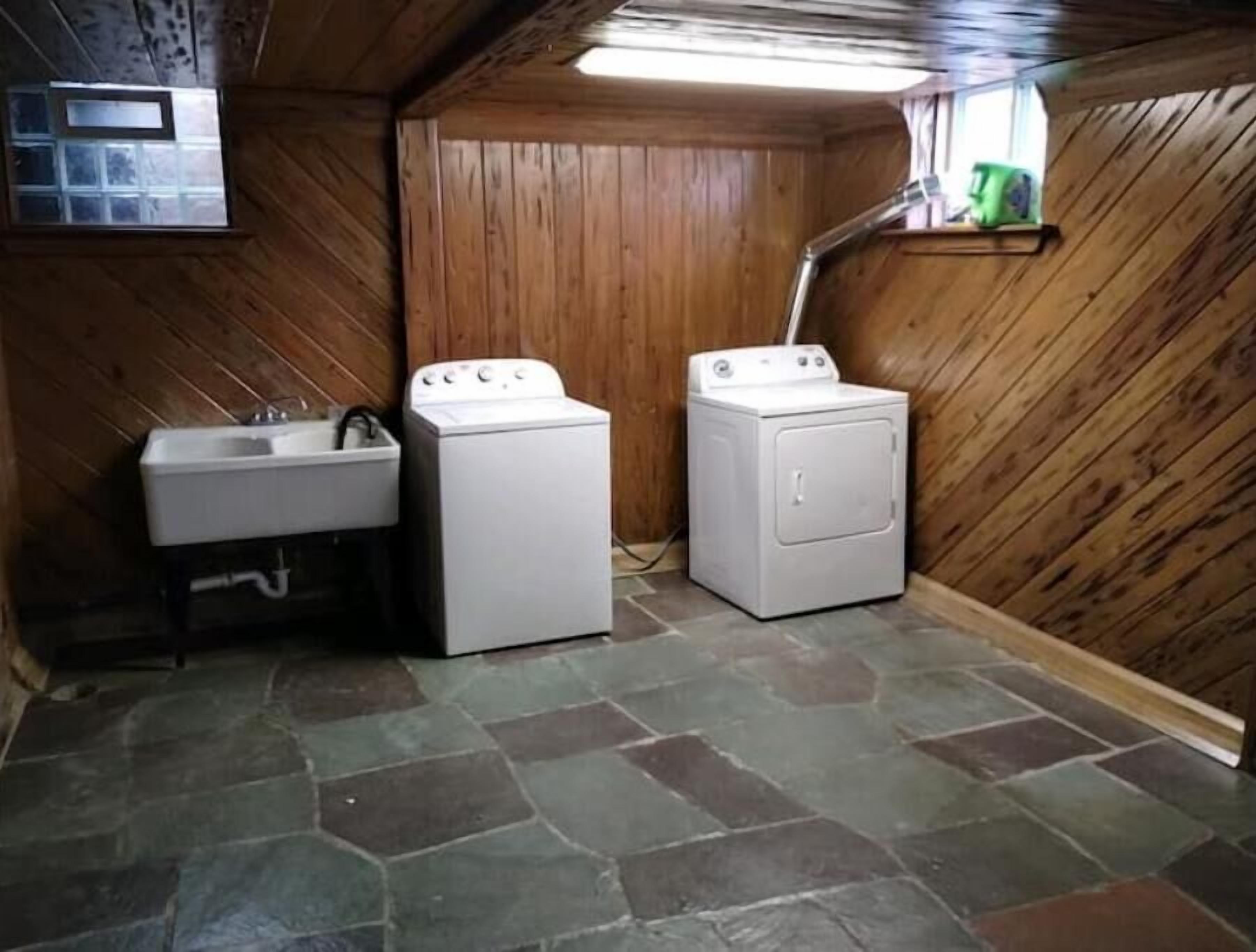 A laundry room with a sink, two washing machines, and a wooden interior.