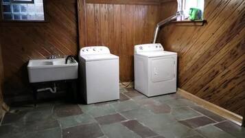 A laundry room with a sink, two washing machines, and a wooden interior.