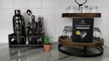 A cocktail station with a guide, a shaker set, a strainer, a jigger, a spoon, and a small potted plant.