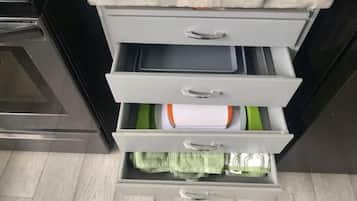 A kitchen with a countertop, a stove, and a drawer with green towels.