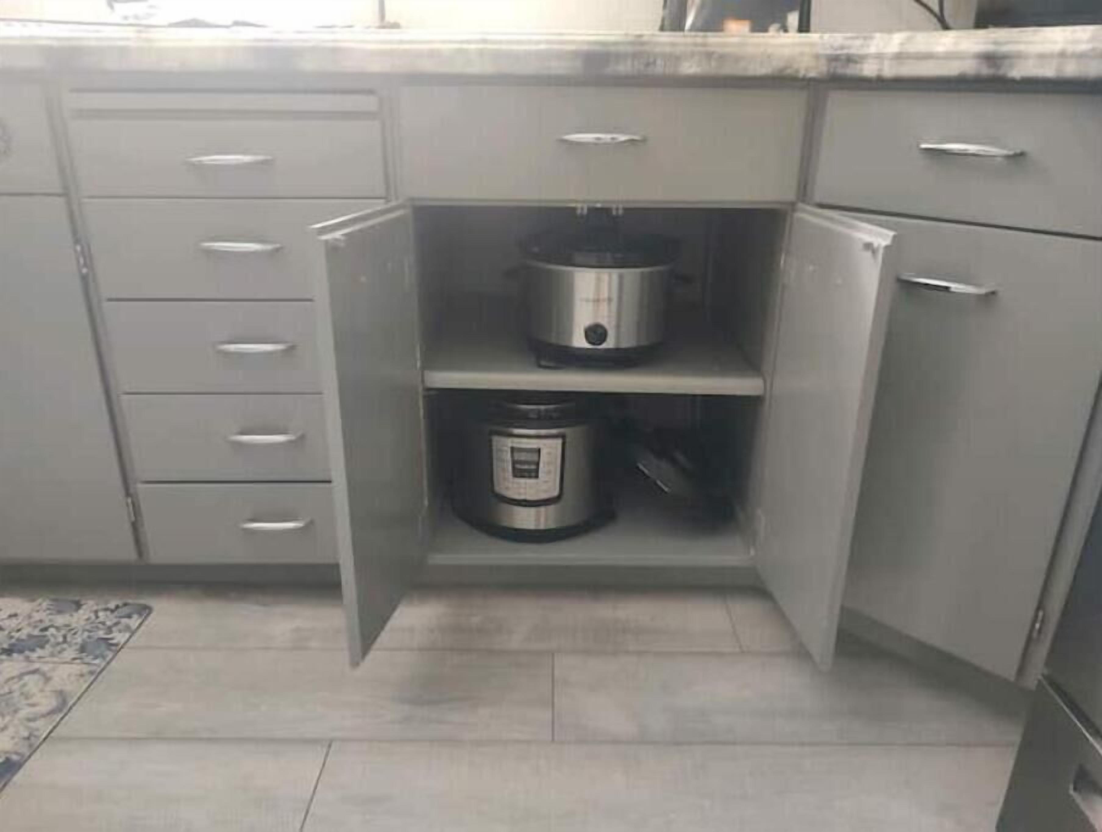 A kitchen with grey cabinets, a countertop, and a built-in oven.