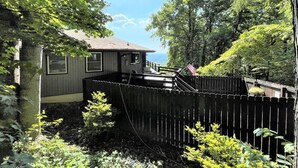 A house with a wooden deck, surrounded by dense foliage and a wooden fence. - Mountain house in Fancy Gap with beautiful view and hot tub on deck (Fancy Gap)