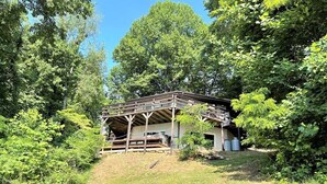 A rustic cabin with a wooden deck, surrounded by dense greenery and trees. - Mountain house in Fancy Gap with beautiful view and hot tub on deck (Fancy Gap)