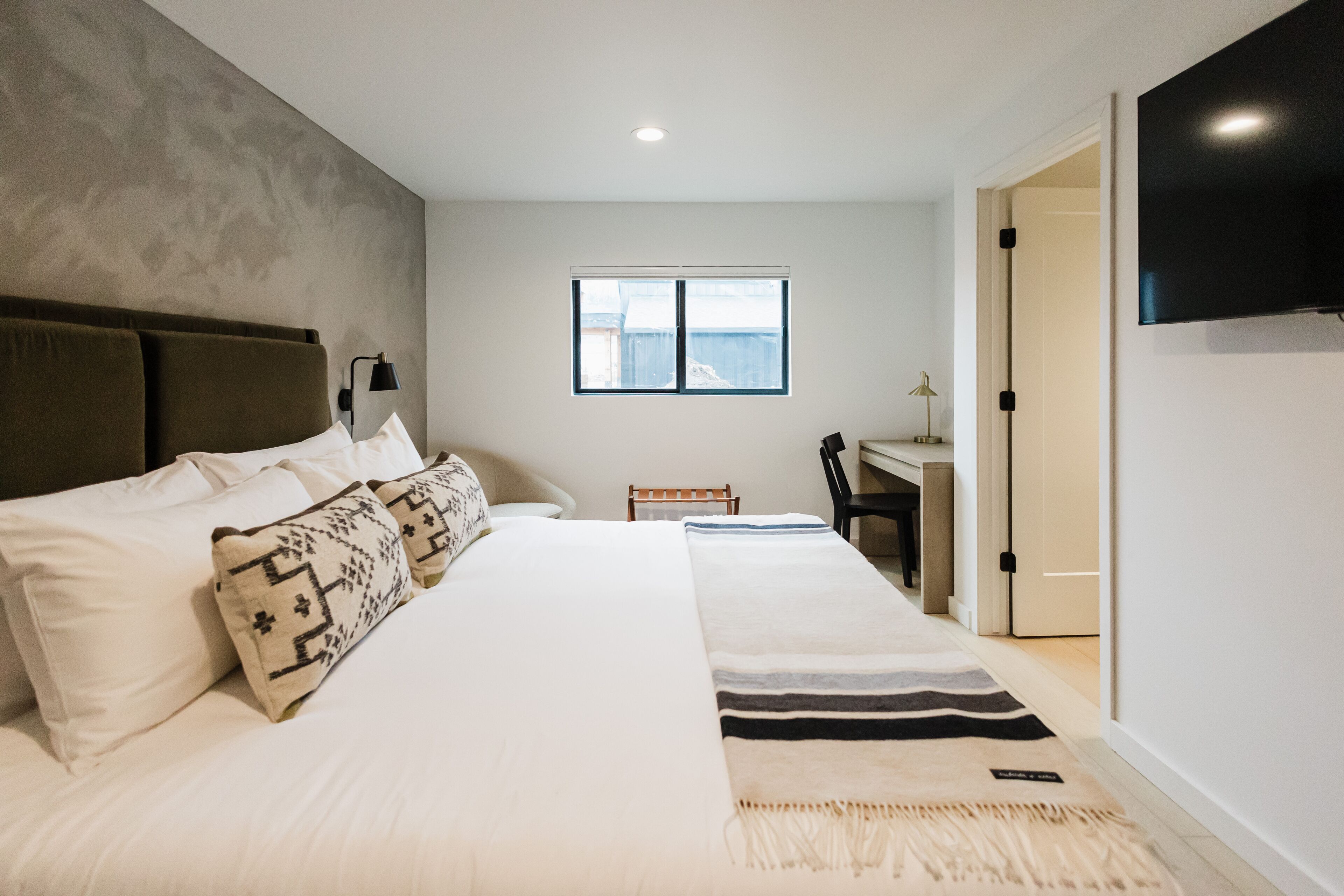 Une chambre moderne avec un grand lit, un bureau et une télévision.