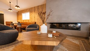 A modern living room with a wooden coffee table, a sofa, and a fireplace. - Wonderstone Hotel - Single King ADA Guest Room (Columbia Falls)