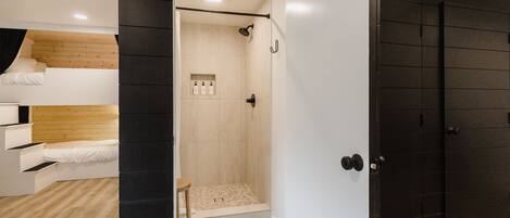 Una habitación moderna con una litera, zona de ducha y un armario negro.