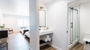 Un baño moderno con cabina de ducha de vidrio, un lavamanos blanco y un inodoro.
