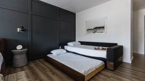 Un dormitorio moderno con piso de madera, una cama con cabecera, una mesita de noche y una lámpara de pared.