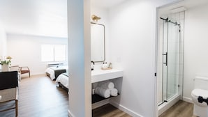 A modern bathroom with a glass shower enclosure, a white sink, and a toilet. - Wonderstone Single King Guest Room (Columbia Falls)