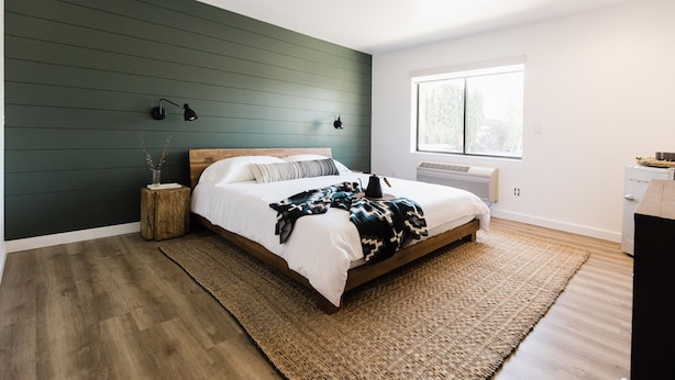 A bedroom with a bed, bedside lamps, a window, and a radiator. - Wonderstone Single King Guest Room (Columbia Falls)