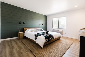 Een slaapkamer met een bed, nachtlampjes, een raam en een radiator.