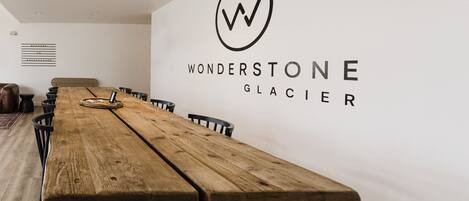 Et langt træbord i et moderne rum med en hvid væg og et logo der siger "WONDERSTONE GLACIER".