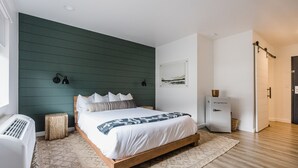 A bedroom with a wooden bed, a green wall, a white radiator, and a small bedside table. - Wonderstone Single Queen ADA Guest Room (Columbia Falls)