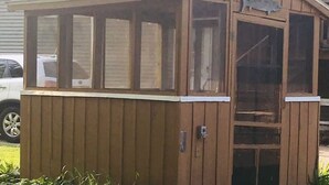 A wooden shed with a door and windows, a metal latch, and a fish symbol on the door.