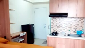 Una cocina compacta con armarios de madera, una encimera y un refrigerador negro.