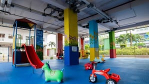 Un área de juegos interior con un tobogán, un coche de juguete verde y un coche de juguete rojo.