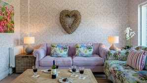 Un salon avec un canapé, une table basse et un élément de décoration murale en forme de cœur.