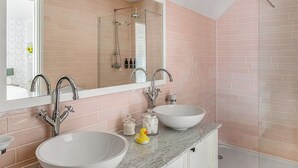 Une salle de bain avec deux lavabos, un grand miroir et une douche.