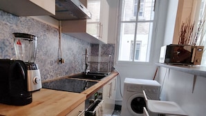 Eine moderne Küche mit Holzarbeitsplatte, einem Einbauofen, einer Waschmaschine und einem Fenster mit Blick nach draußen.