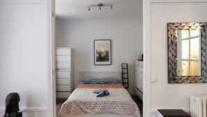 Ein Schlafzimmer mit einem Bett, einem Heizkörper, einem Heizgerät, einem Schminktisch und einem Spiegel.