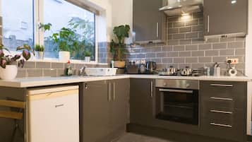Una cocina moderna con lavavajillas, horno y ventana con plantas.