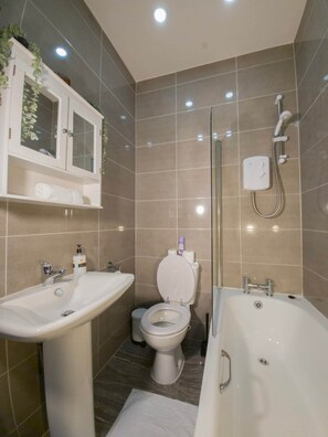 A modern bathroom with a bathtub, a sink, a toilet, and a shower.