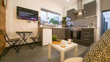 A modern kitchen with grey cabinets, a built-in oven, and a large window.