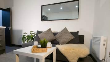 Ein modernes Wohnzimmer mit einer Couch, einem Couchtisch und einem großen Spiegel an der Wand.