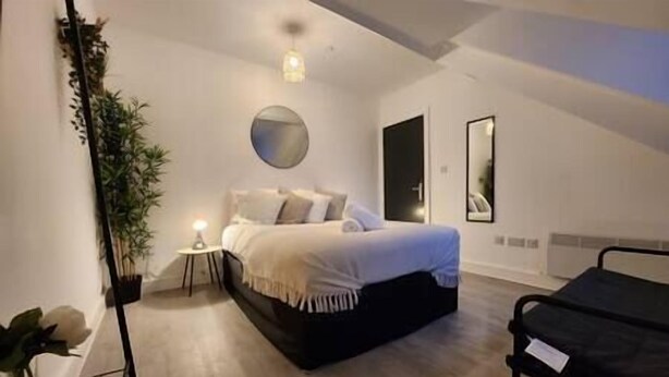 A bedroom with a bed, bedside table, lamp, and a mirror on the wall. - ApartHotel - Flat 7 (1 bed) (Cardiff)