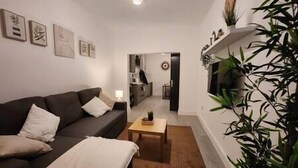 A living room with a sofa, a coffee table, and a plant. There are framed pictures on the wall. - ApartHotel - Flat 6 (1 bed) (Cardiff)