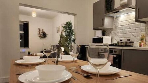 A dining area with a wooden table set for four, including wine glasses and plates. - ApartHotel - Flat 6 (1 bed) (Cardiff)