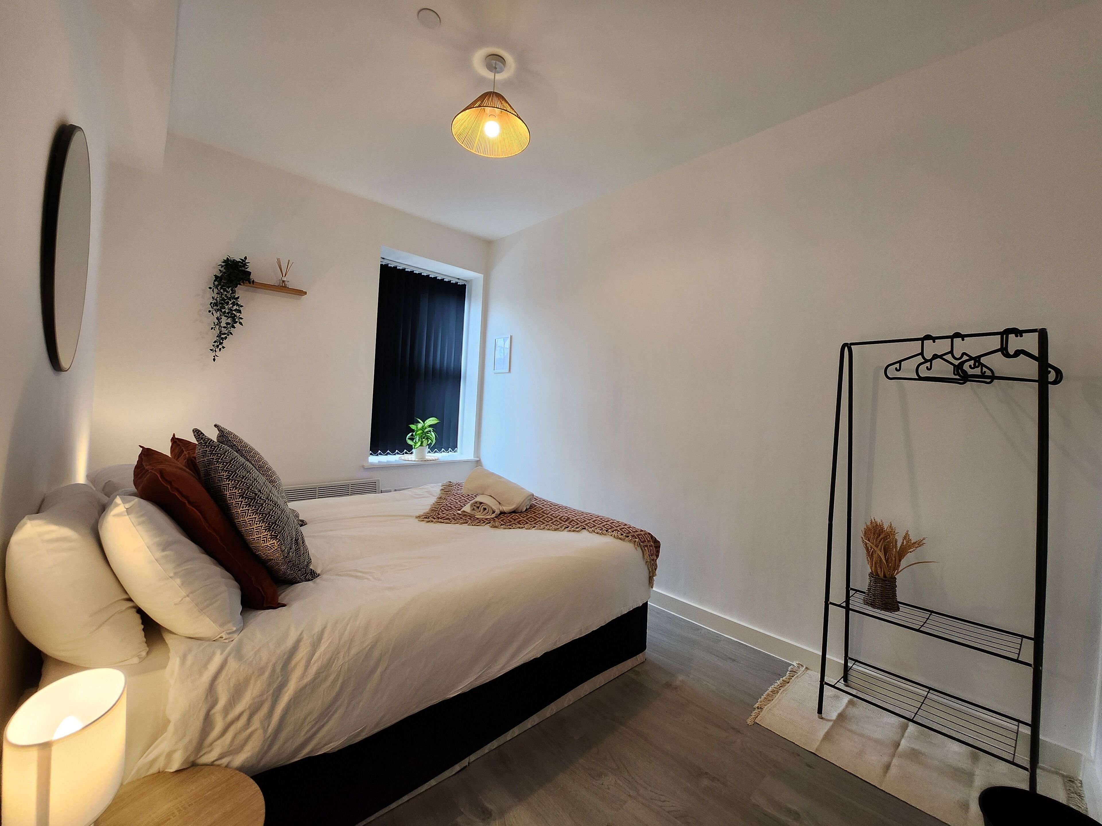 Un dormitorio moderno con cama, mesita de noche y una planta colgante.