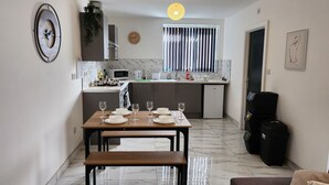 A modern kitchen with a dining area, a small refrigerator, and a bench. - ApartHotel - Flat 8 (2 bed) (Cardiff)