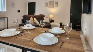 A dining area with a wooden table set for four, white plates, bowls, and wine glasses. - ApartHotel - Flat 8 (2 bed) (Cardiff)