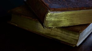 Una pila de libros antiguos y desgastados, con páginas y cubiertas a la vista.