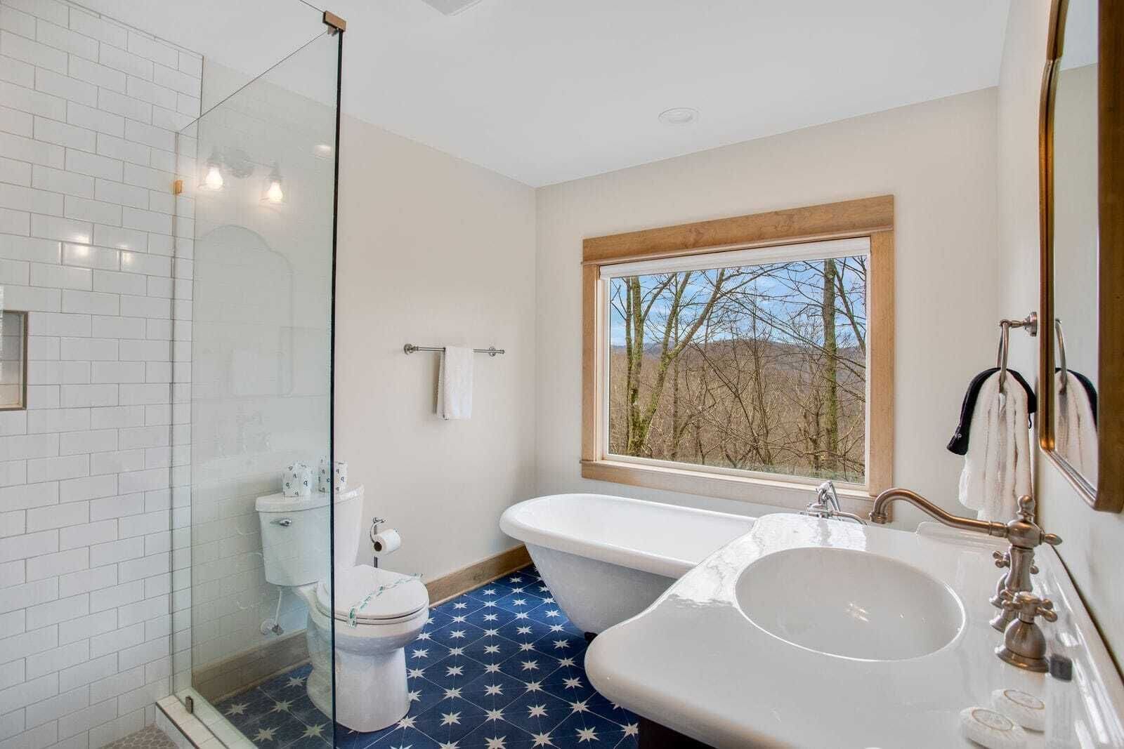 A bathroom with a glass shower enclosure, a toilet, a bathtub, and a sink.