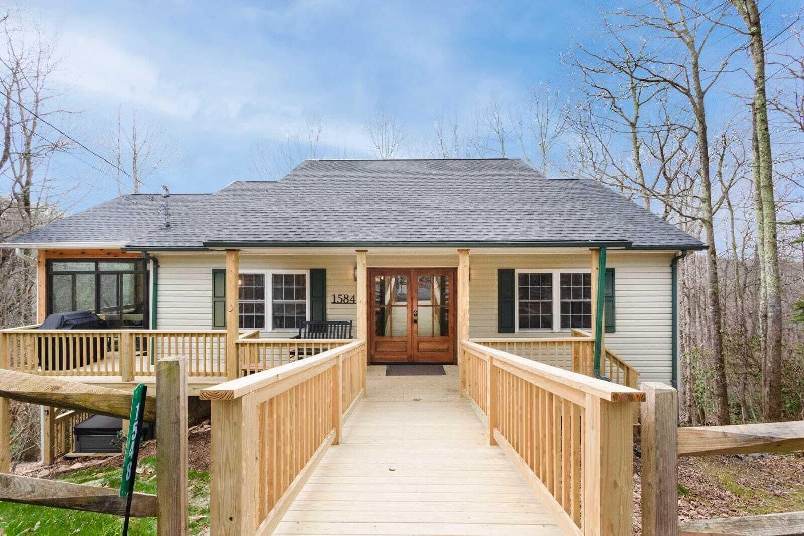 A two-story house with a covered porch, a wooden deck, and a number '1584' on the front door.